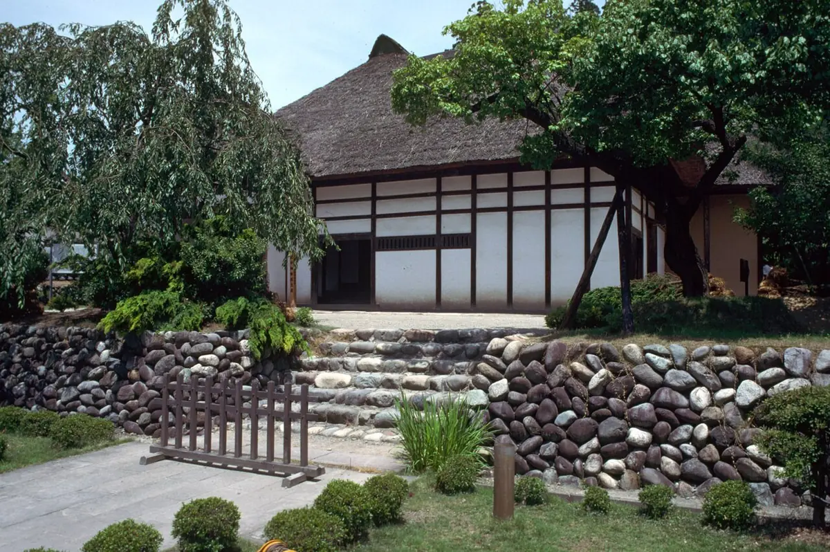 Historic Aizu samurai residence surrounded by trees and stonework