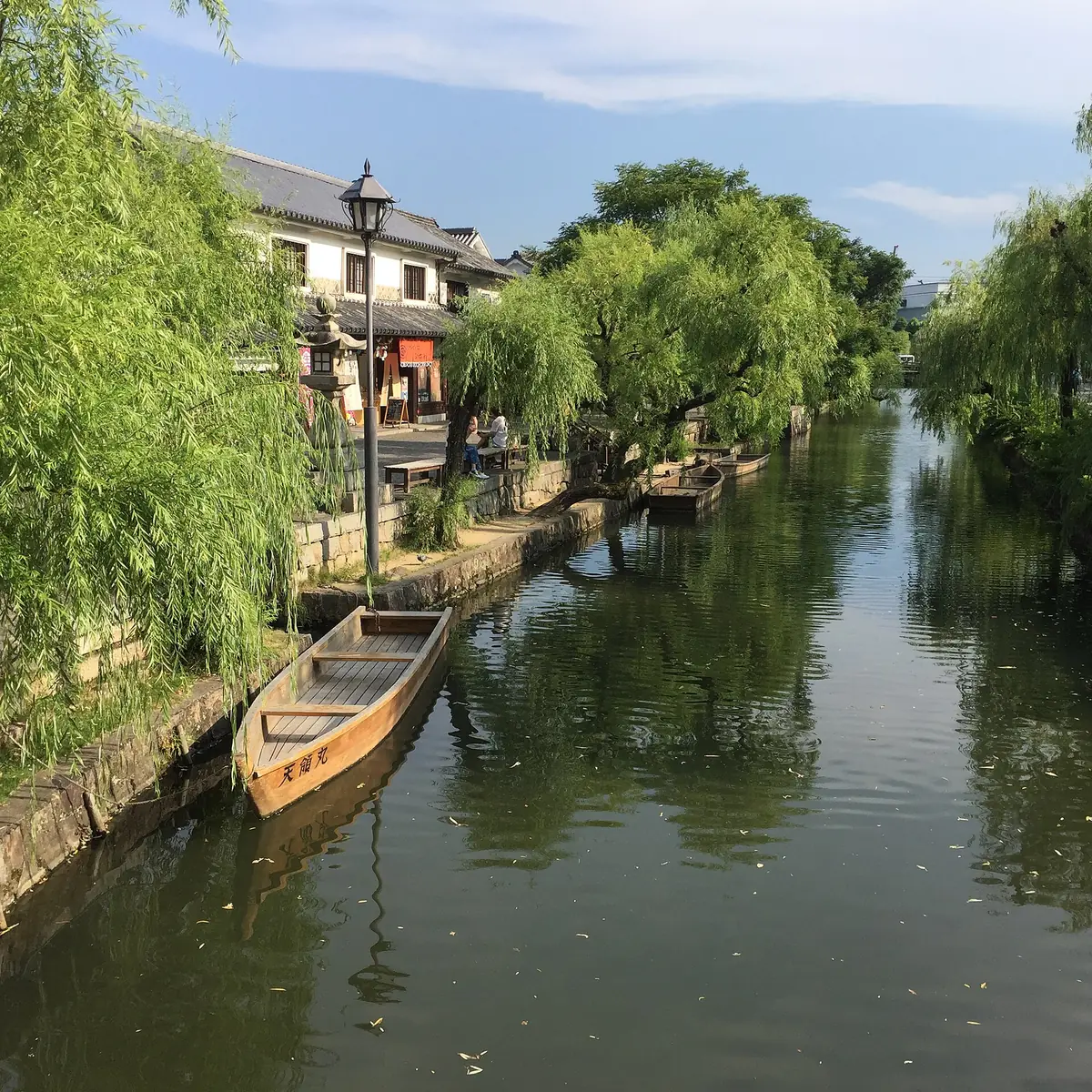 Willow trees and historic white-walled buildings along the Kurashiki Canal