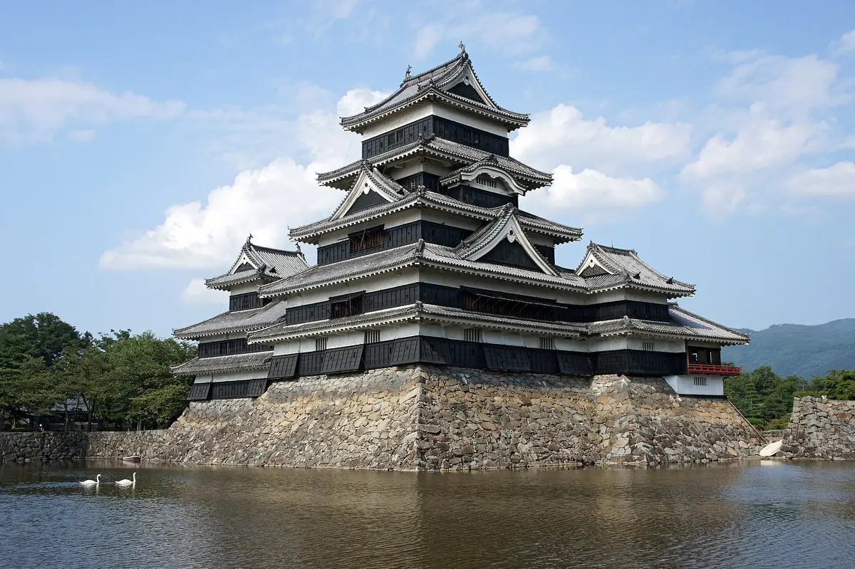 Matsumoto Castle reflected in its moat beneath a blue sky
